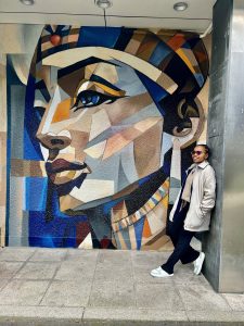 Haikaeli standing in front of a large mural.