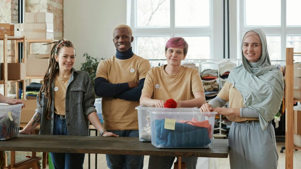 A group of young people standing in front of boxes full of clothes.